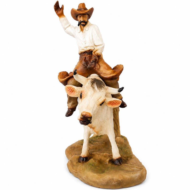 Statue of a cowboy riding a bull on a white background