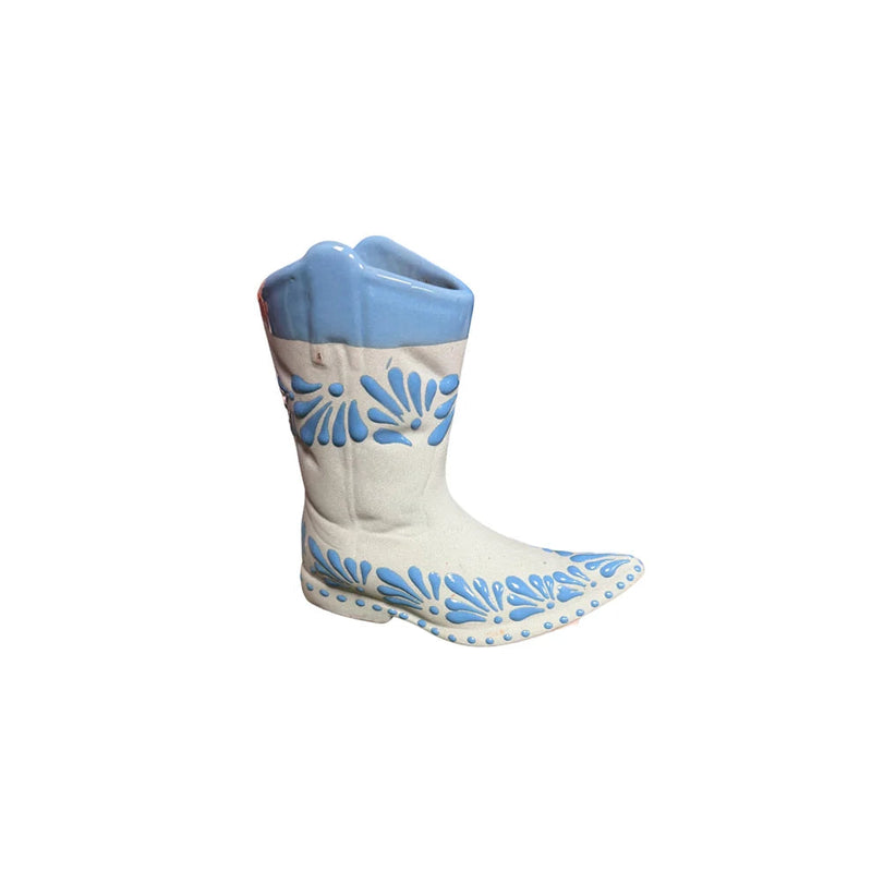 A ceramic cowboy boot figurine with a white body, light blue shaft, and blue floral patterns, set against a plain white background.